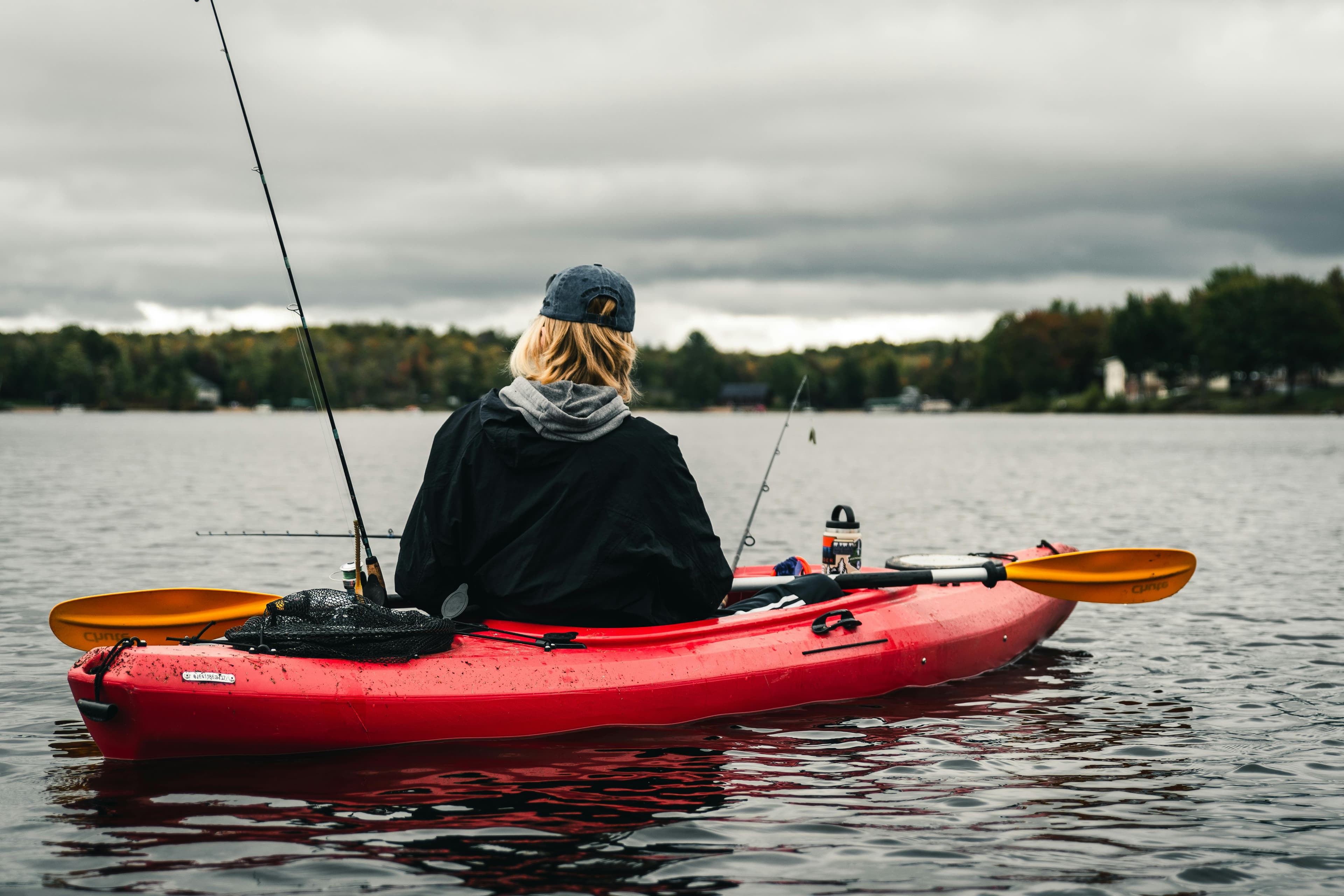 Kayak outrigger stabilizers mounted on a sit-on-top fishing kayak on calm water